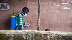 Health worker in Freetown, Sierra Leone sprays disinfectant around Ebola infected reside before loading him into an ambulance.