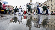 Members of a traditional Bavarian costume association (Trachtenverein) participate, reflected by rain puddles, in the annual riflemen's parade of the Oktoberfest 2016 beer festival in Munich, Germany.