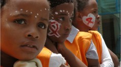 Three children with AIDS ribbon symbol painted on their cheeks 