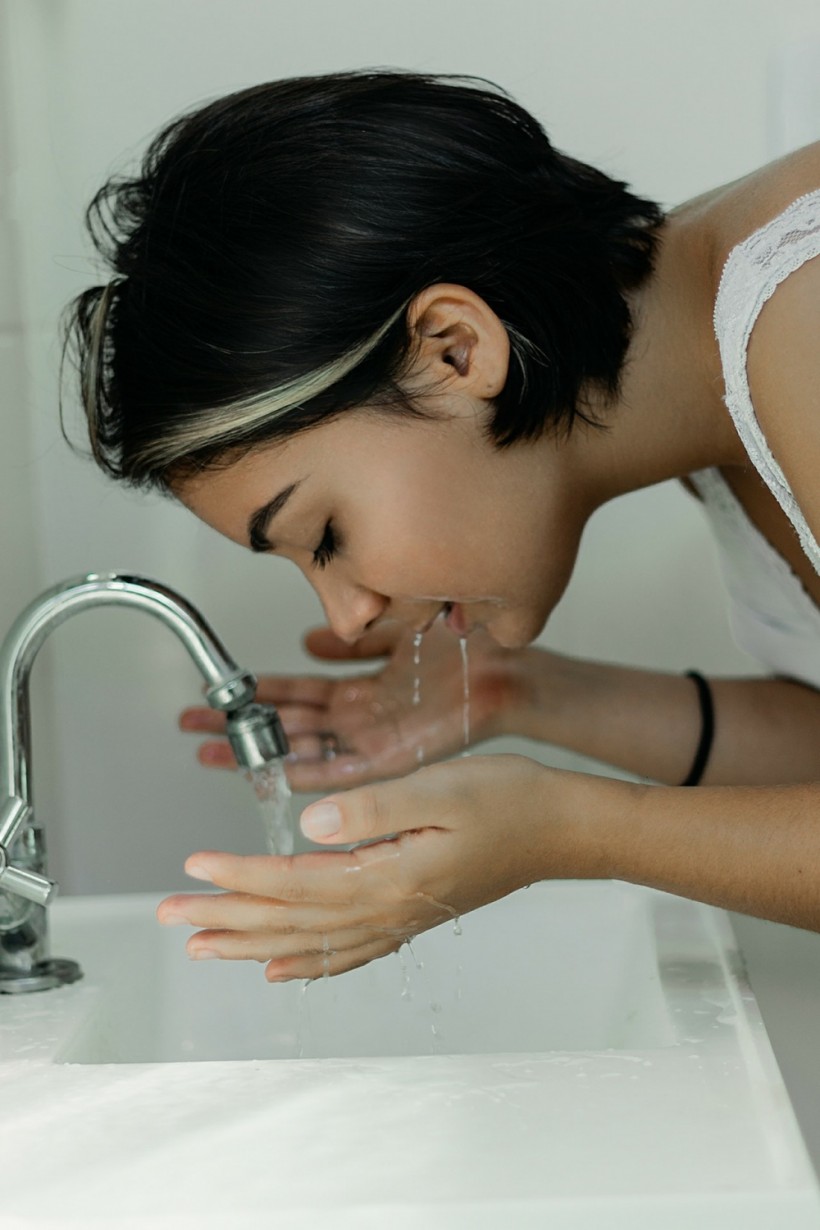 A woman is washing her face.
