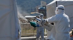 Quarantine workers in protective gear spray disinfectants at a screening facility for checking coronavirus disease (COVID-19) in Cheongdo county