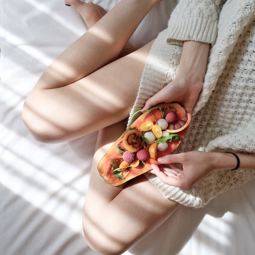 Women holding fruit in bed
