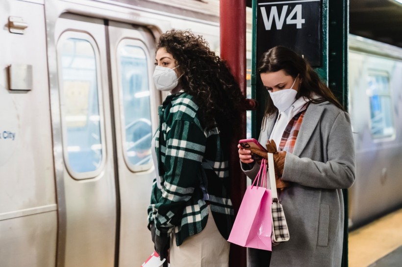 girlfriends-in-masks-using-cellphone-in-underground-station-near-train-6567595