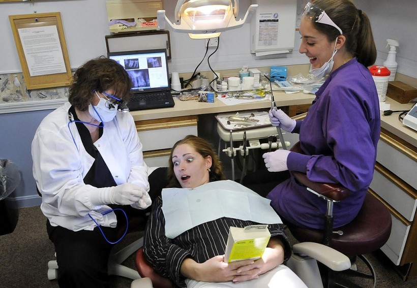 Patient Adriane Williams of Portland reacts as she is shown a wisdom tooth with a cavity
