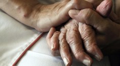 A nurse holds the hands of a person suff