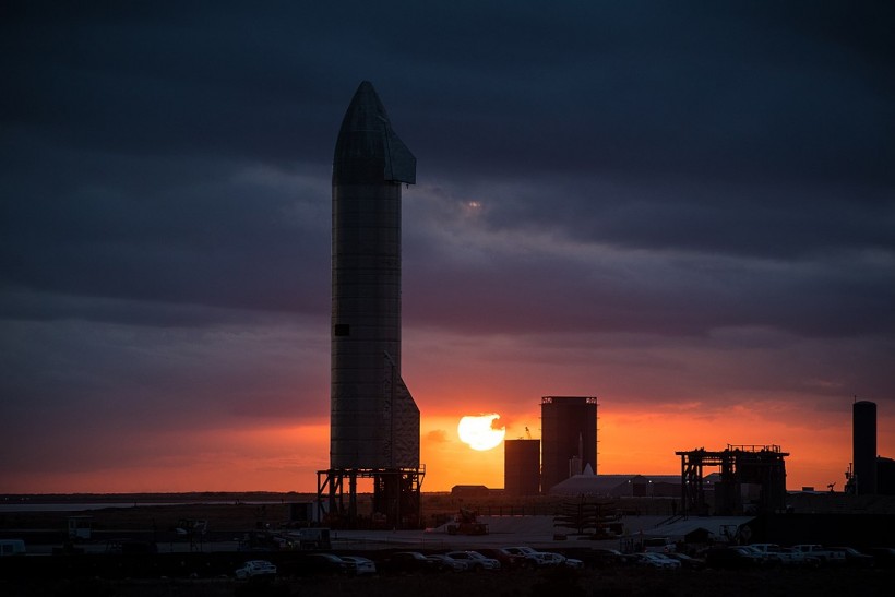 The silhouette of Starship SN9 and the build site at sunset.