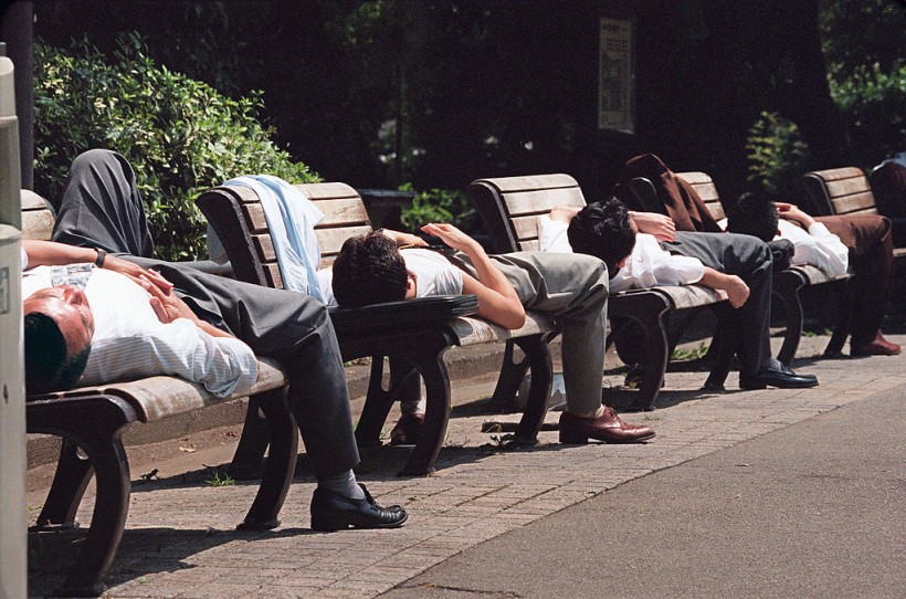 Japanese businessmen take naps on benches in Hibiya Park