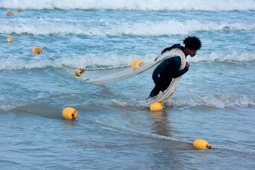 Men fishing from the beach on False Bay at Muizenburg in the