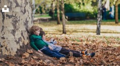 Two children sitting on ground with dried leaves photo
