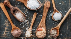 Wooden spoons with different sorts of salt - stock photo