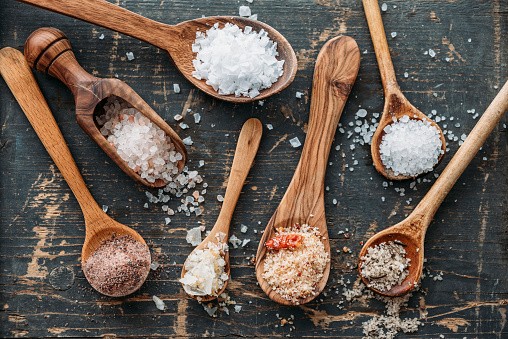 Wooden spoons with different sorts of salt - stock photo