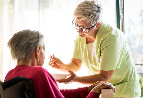 Taking care of elderly sick woman in wheelchair - stock photo