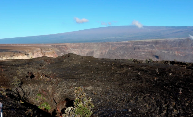 Hawaii's Mauna Loa volcano, background, towers over the summit crater of Kilauea volcano in Hawaii Volcanoes National Park on the Big Island on April 25, 2019. 