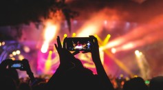 person holding smartphone taking video of a concert near 
