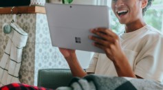 Man at home wearing pyjamas smiling at surface laptop screen 