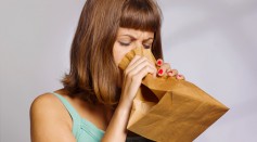 woman having a panic attack using paper bag to calm herself