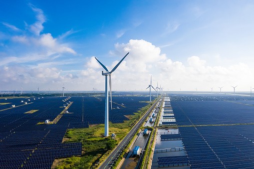 Solar power stations in plain areas, wind turbines in the distance. Yancheng City, Jiangsu Province, China. - stock photo