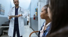Man in White Medical Scrub Suit Standing Beside Girl in Blue Denim Jacket