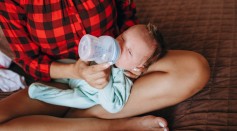 Unrecognizable mother bottle feeding infant