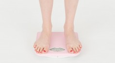 Woman checking weight on scales in studio