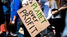 woman holding Planet over Profit placard