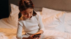 child using cellphone on bed
