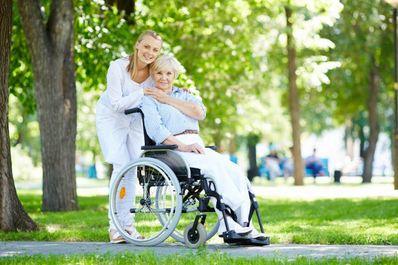 Nurse hugging elderly woman in wheelchair