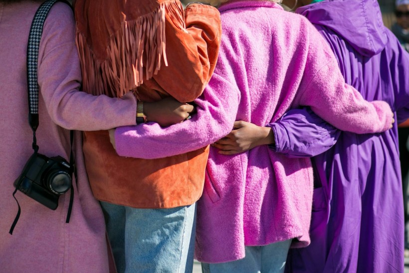 four persons holding each other's waist at daytime