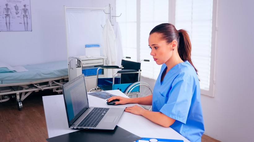 Nurse analysing list of patients on laptop