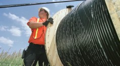 Reeltender Mo Laussie watches fiber-optic cable as he helps install the cable unto telephone poles June 21, 2001 in Louisville, CO.