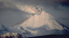 View, looking west, of 1,312-m (4,304 ft)-high Kanaga Volcano in eruption. Kanaga is located about 25 km (16 mi) west of the U.S. Navy installation and port on Adak Island in the Aleutian Islands.