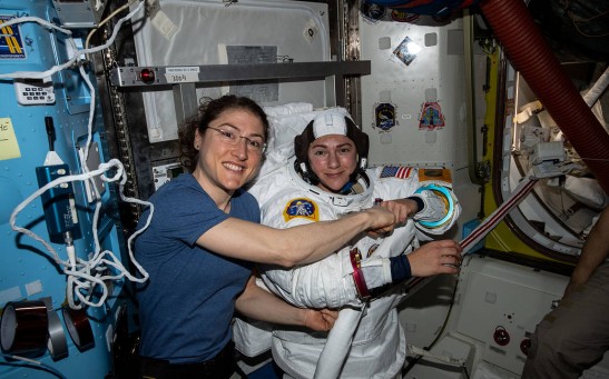 Expedition 61 Flight Engineers Christina Koch (left) poses for a photo with colleague Jessica Meir (right) while preparing for the first all-women spacewalk in history.