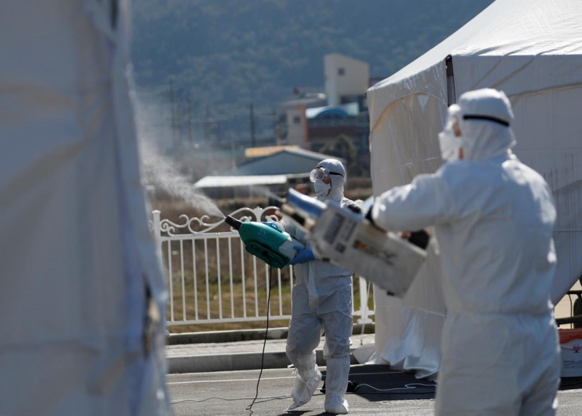 Quarantine workers in protective gear spray disinfectants at a screening facility for checking coronavirus disease (COVID-19) in Cheongdo county