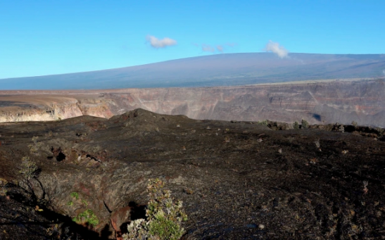 Hawaii's Mauna Loa volcano, background, towers over the summit crater of Kilauea volcano in Hawaii Volcanoes National Park on the Big Island on April 25, 2019. 
