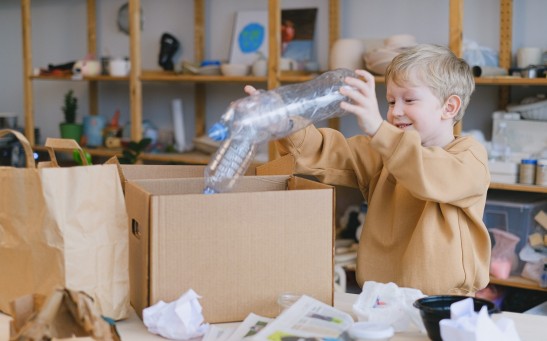 Smiling Boy Putting Plastic Bottles on a Box