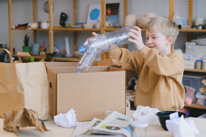 Smiling Boy Putting Plastic Bottles on a Box