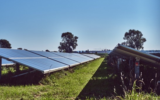 black solar panels on green grass field under blue sky during daytime