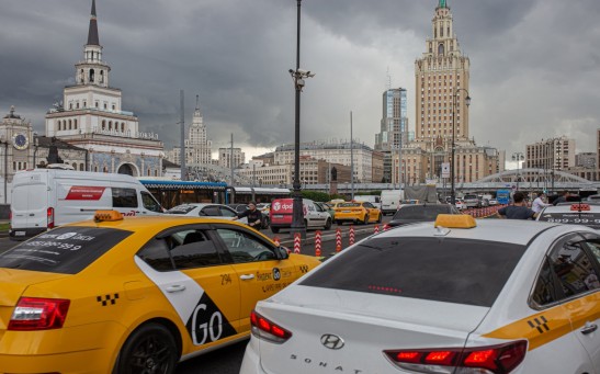 white and yellow taxi cab on road near city buildings during daytime