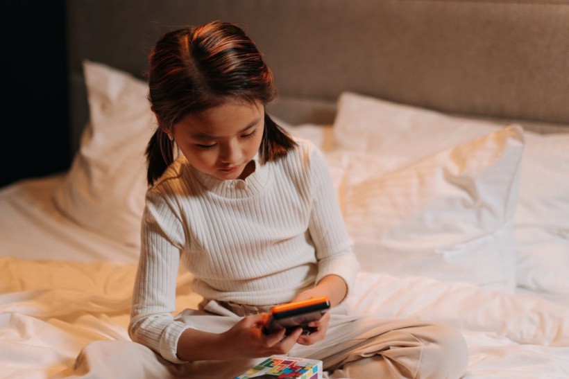 child using cellphone on bed