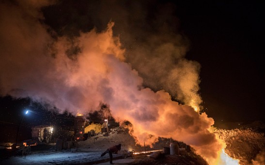 A Chinese labourer pours steel as fire is seen in a cooling pit at an unauthorized steel factory on November 3, 2016 in Inner Mongolia, China.