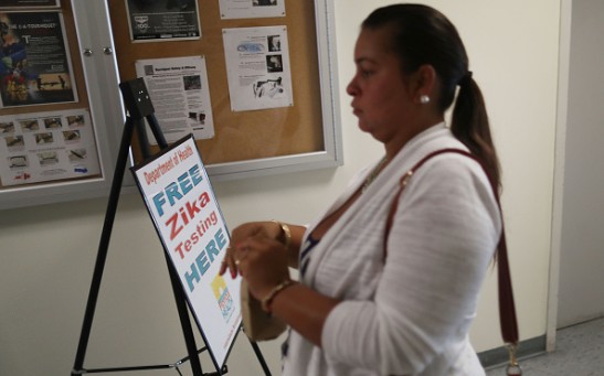 Krystal Cruz, who is pregnant, carries her urine sample as she gets a free Zika test from the Florida Department of Health that has setup a temporary clinic at the Miami Beach Police Department.